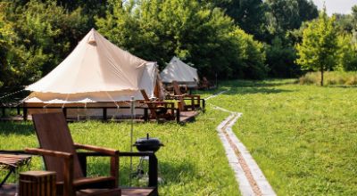 tents-with-wooden-chairs-pathway-front-them-glamping-nature-greenery-around